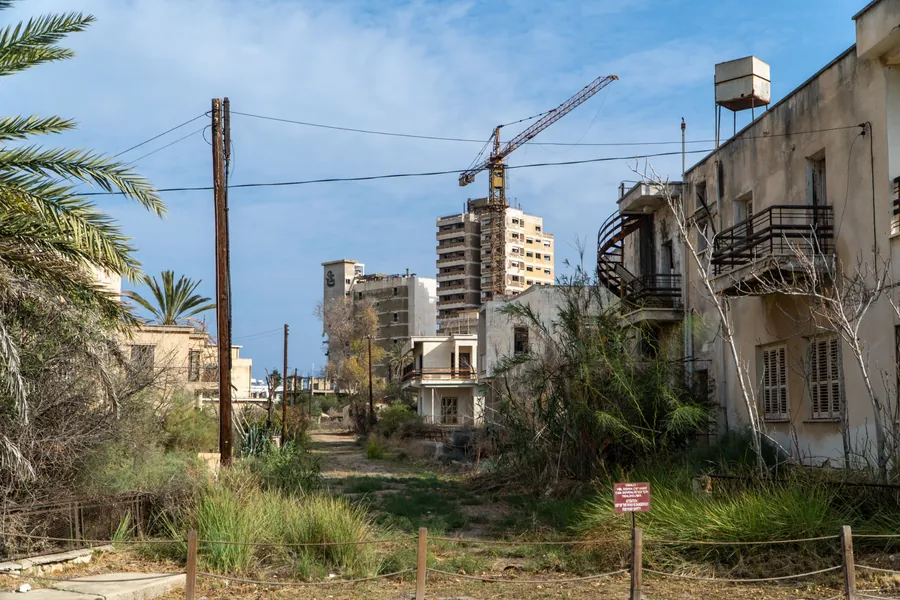 An overgrown street with a rusting crane and abandoned hotels